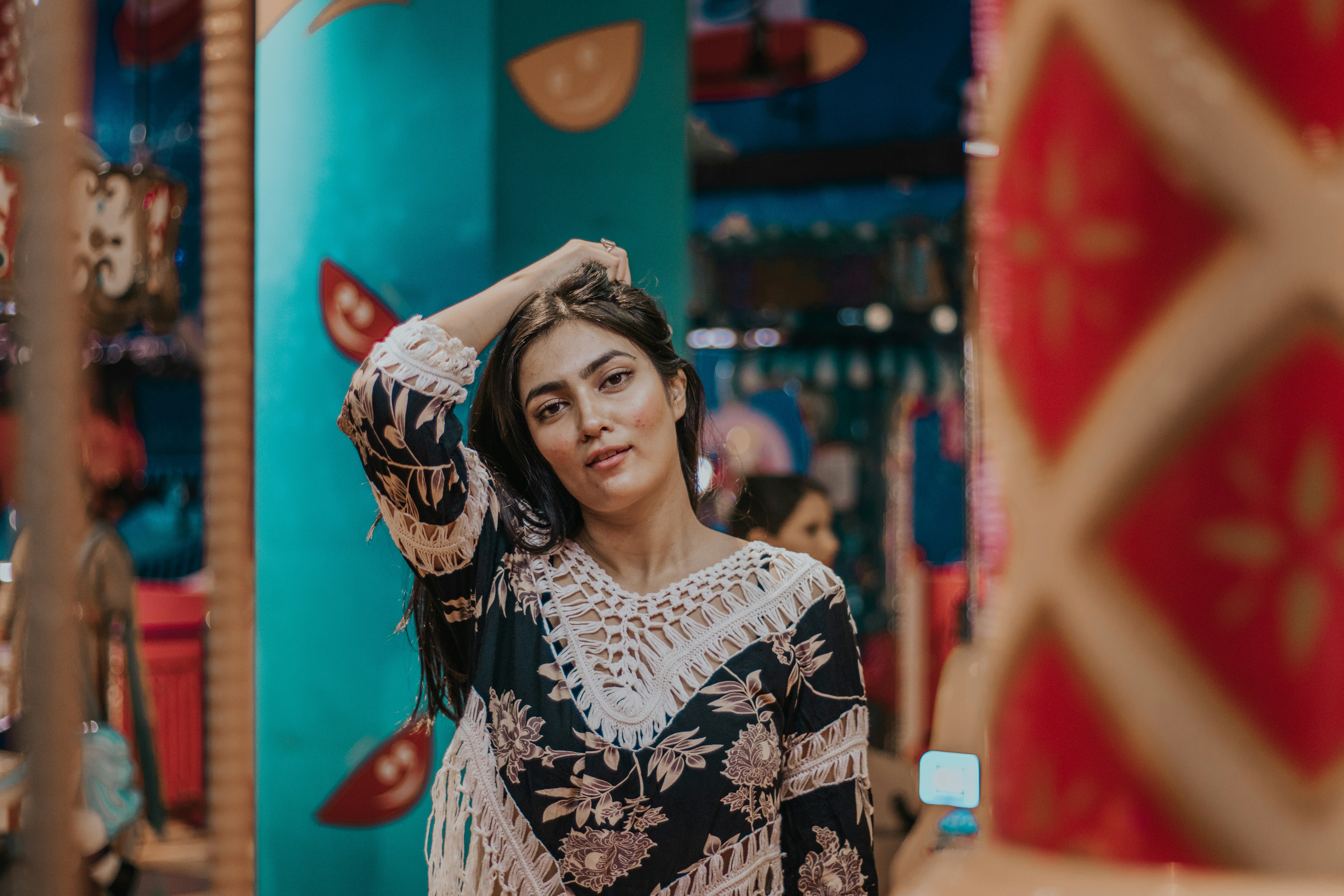 woman in black and white floral long sleeve shirt standing near red wall